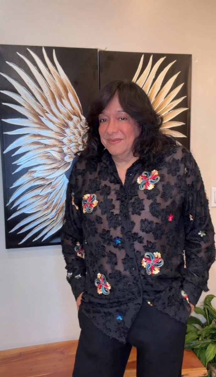 Michelle, master stylist, in front of the gold wings wall